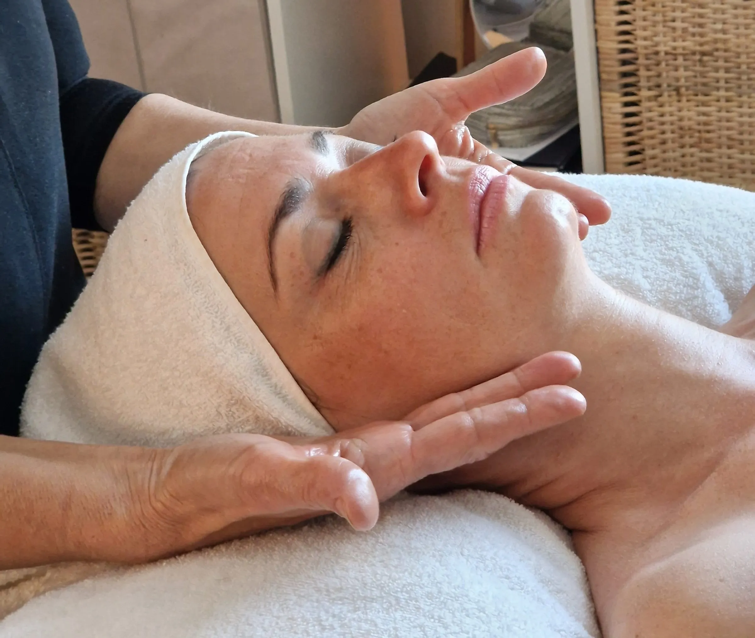 Les mains de Karine posées sur le visage d'une cliente pendant un soin